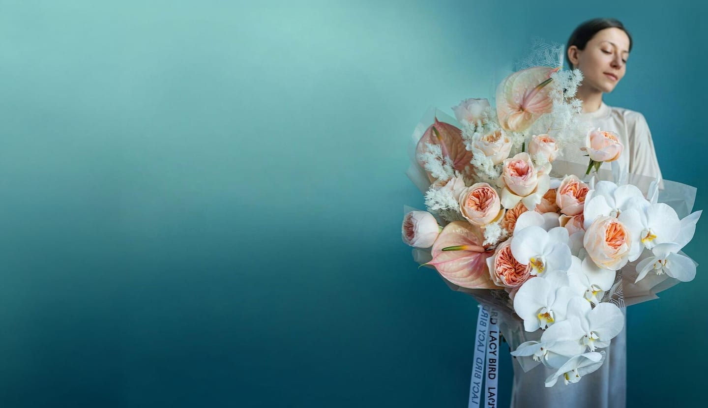Florist holding a signature peach-and-white bouquet
